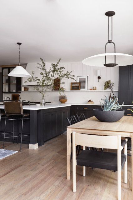 a refined modern farmhouse kitchen with black lower cabinets and a kitchen island, an open shelf with decor and pendant lamps