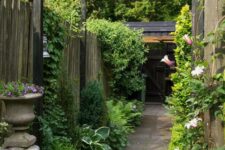 a refined vintage-inspired side yard with a pavement path, greenery and blooms, climbing plants and a vintage urn with blooms
