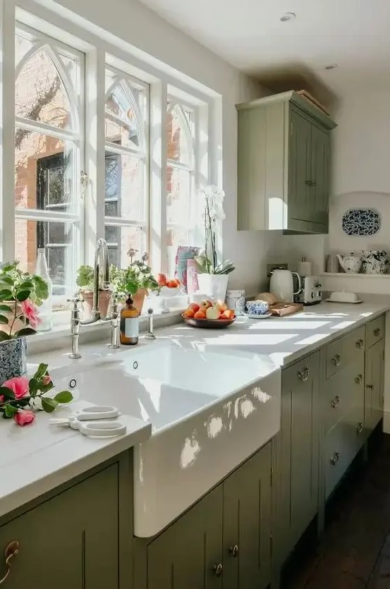 a sage green farmhouse kitchen with white stone countertops, a single upper cabinet, vintage fixtures and a vintage sink