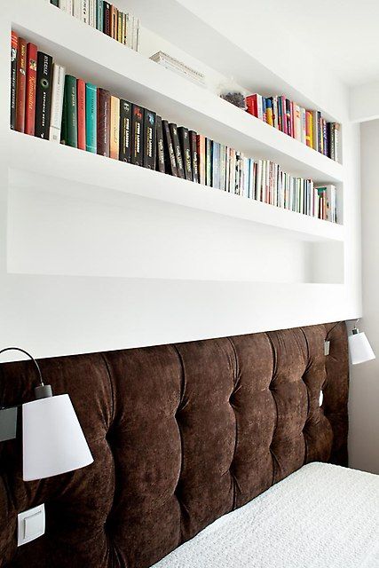 a series of niches used as bookshelves and to place the headboard of the bed with sconces is lovely for a small bedroom