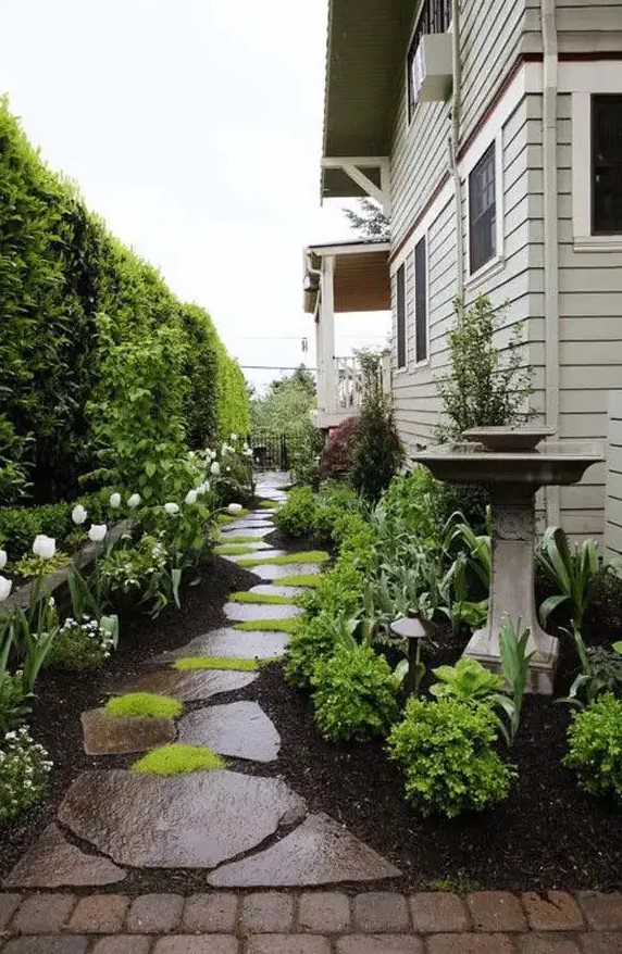 a side yard with an irregular stone path, some grenery and blooms, a bird bath and a living wall is amazing