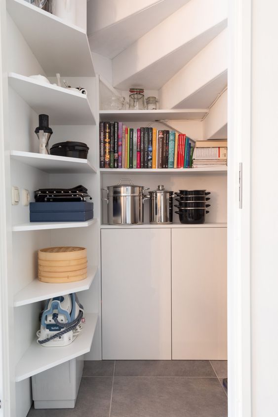 a small and cool staircase pantry with a sliding door, with built-in shelves and cabinets is a functional idea for every home