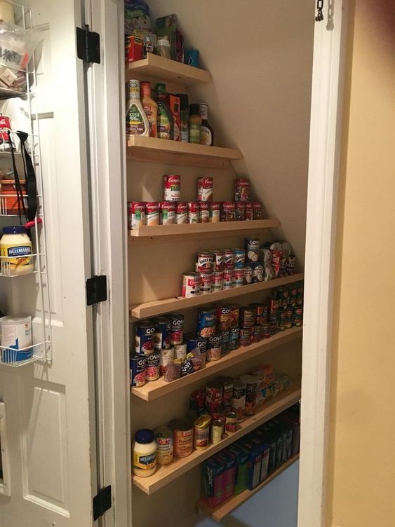 a small and cool under stairs pantry with ledges and shelves that allow storing canned food is a very practical solution