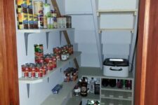 a small and well-organized stairs pantry with open shelves and a built-in storage unit, with food and drinks stored