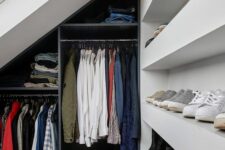 a small attic closet with open shelves for shoes, a navy open storage unit with railings and a skylight is a cool solution
