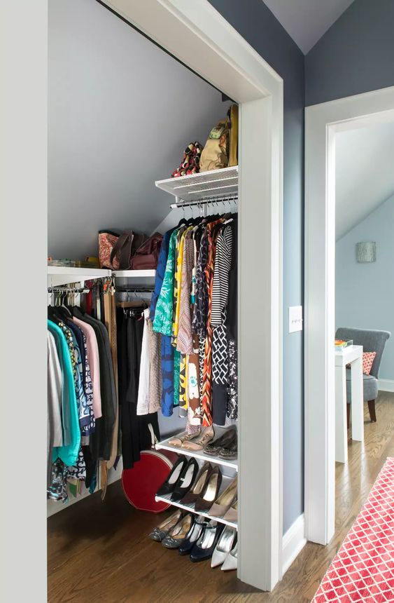 a small attic closet with railing, open shelves and bags is a lovely solution for a bedroom