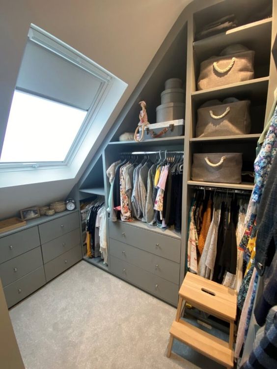 a small grey attic closet with open storage compartments and drawers, railing for clothes is a lovely and cozy space