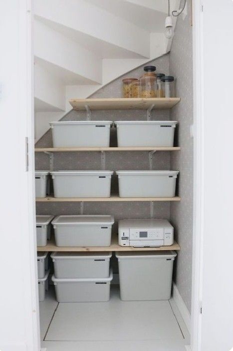 a small staircase pantry with a sliding door, a shelving system and plastic containers for a seamless and sleek look