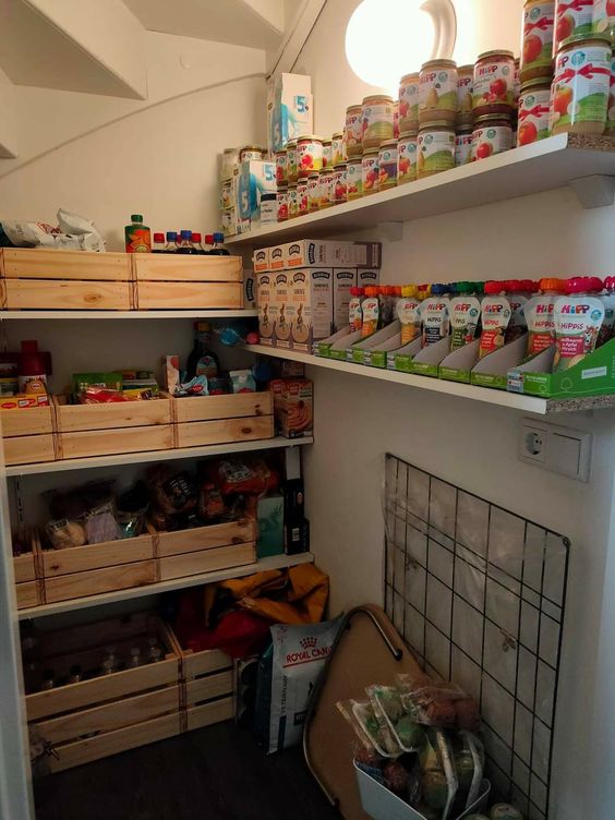 a small staircase pantry with open shelves, crates and boxes with food is a cool solution to save a lot of space