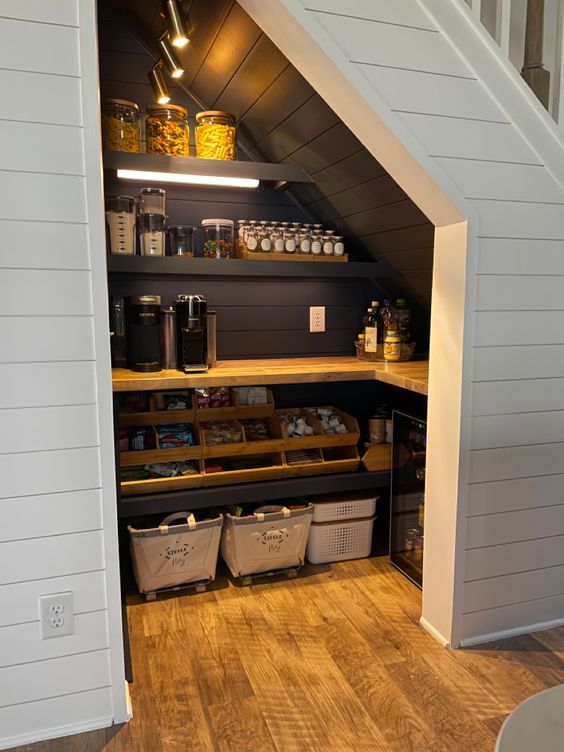 a small yet stylish farmhouse pantry with black shiplap inside, built-in shelves and a countertop, cubbies and a wooden shelf