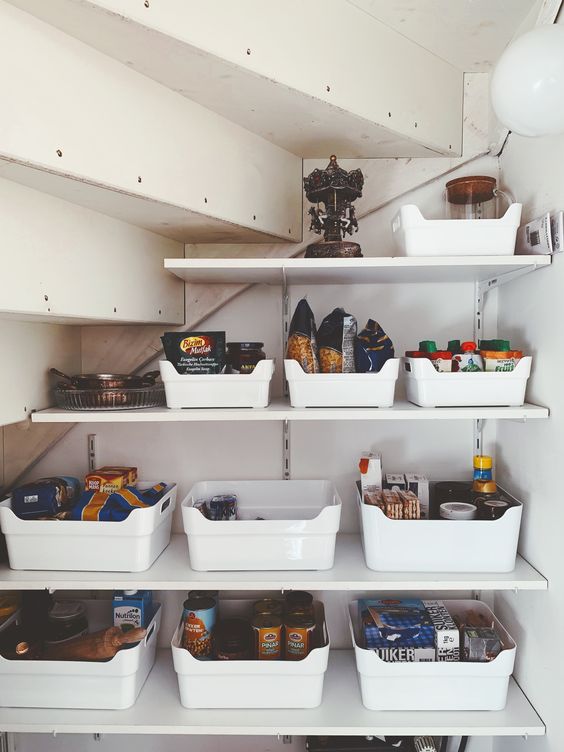 a small yet well-organized under stairs pantry with open shelves and plastic cubbies is a cool solution to save your space
