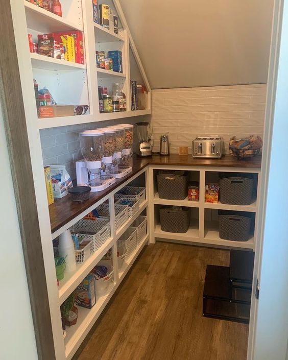 a smart staircase pantry with a built-in storage unit with shelves and more shelves over it, with cubbies and all the necessary stuff here