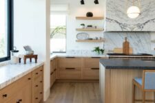 a sophisticated modern farmhouse kitchen with stained lower cabinets, a stained kitchen island, white marble countertops and a hood clad with marble