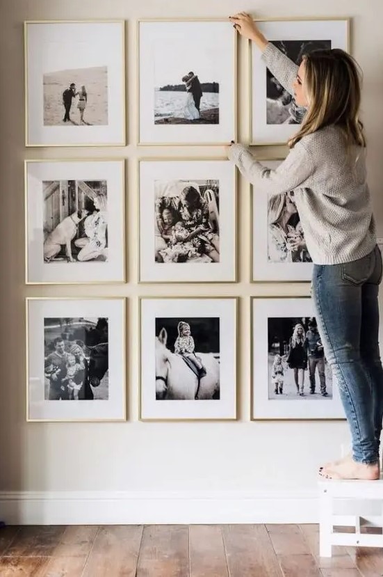 a stylish and elegant gallery wall with black and white family pics in gilded frames is a pretty solution for your home