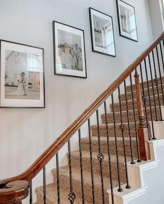 a stylish and laconic gallery wall of wedding photos in matching frames is a cool solution to fill in a blank staircase wall