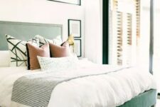 a stylish bedroom with a green upholstered bed, printed bedding, a printed rug aand green window frames