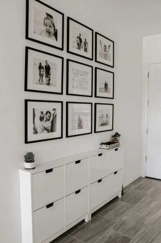 a stylish symmetrical black and white gallery wall with matching black frames and black and white family pics is a chic idea