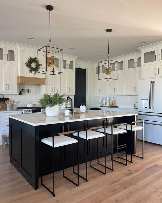 a stylish white kitchen with a black kitchen island, white stone countertops and a tile backsplash, tall stools and pendant lamps