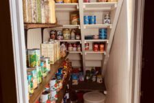 a tiny pantry under the stairs with open and built-in shelves, with plastic containers and various types of food tored