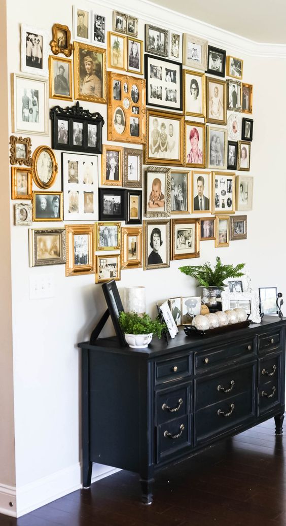 a vintage sideboard with potted greenery and decor and a free form gallery wall completely composed of vintage family photos