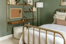 a welcoming bedroom with sage green walls, a brass bed with neutral bedding, a shelving unit with a desk