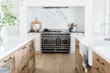 a welcoming modern farmhouse kitchen with white and stained cabinets, white stone countertops, wooden beams and a black cooker