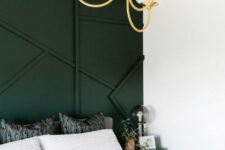 a white bedroom with a dark green paneled wall, a black nightstand, a gold chandelier and some lovely decor