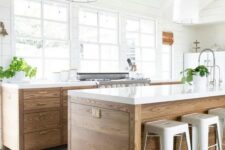 an airy modern farmhouse kitchen with stained cabinets and a kitchen island, white stone countertops, pendant lamps