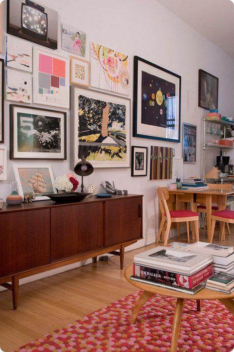 an eclectic space with a stained credenza, a bold pompom rug, some mid-century modern furniture and a bright free form gallery wall