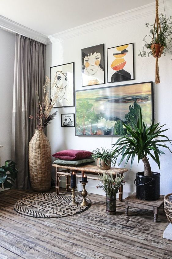 an eye-catching space with a woven bench, a free form gallery wall, potted greenery, a boho rug and bold pillows