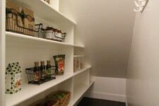 an under stairs pantry with a built-in shelving unit with baskets and wire baskets plus hooks on the walls