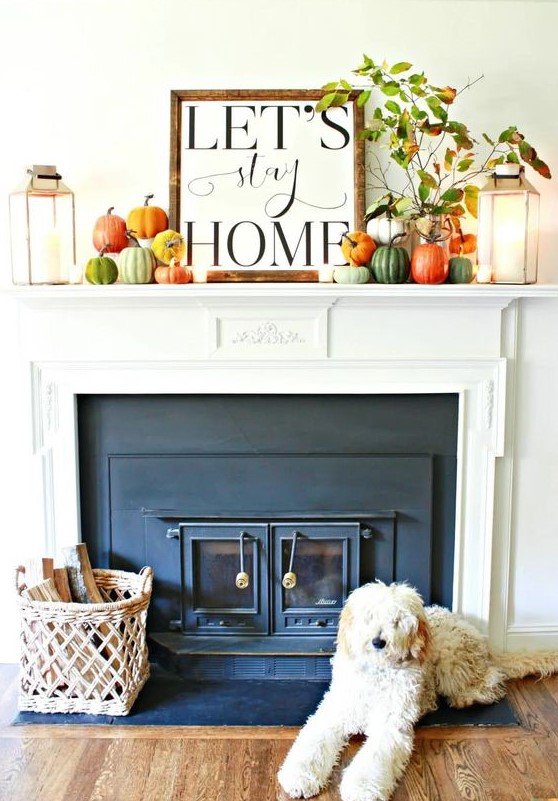 a bright and cool fall rustic mantel with lots of colorful pumpkins, fall leaf branches and candle lanterns plus a sign on top