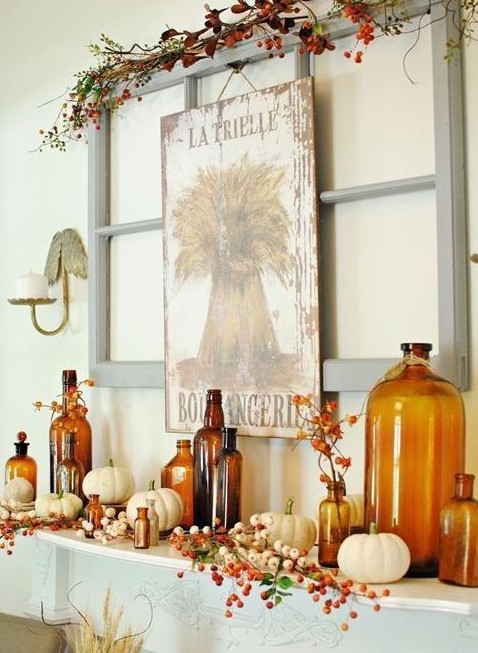 a bright fall mantel with a vintage sign, faux berries and branches, white pumpkins and amber-colored bottles