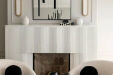 03 a contemporary space with a fireplace with a reeded surround, an arched mirror, creamy chairs, a black tube chandelier and black pillows