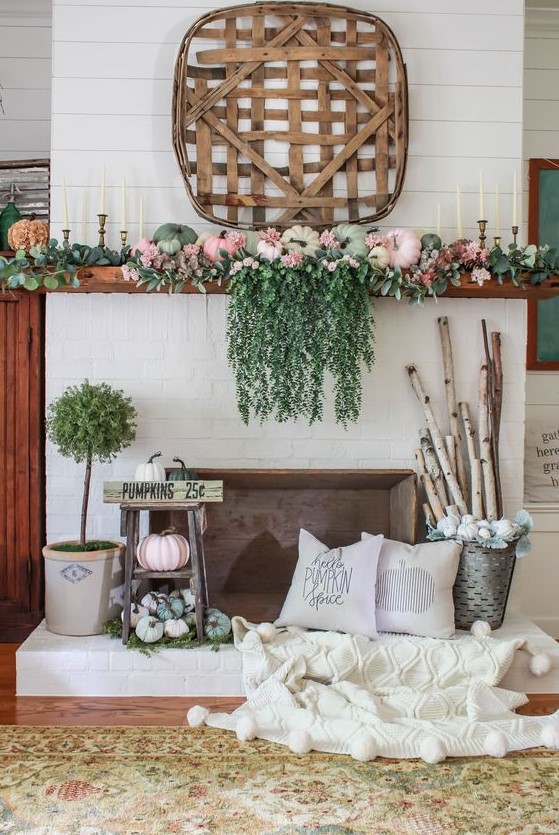 a bright fall mantel with cascading greenery, pastel pumpkins, greenery, branches in a bucket and a wooden basket