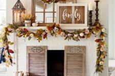05 a bright rustic fall mantel with a reclaimed sign, bright leaves and pumpkins, candle lanterns, wooden candleholders with pillar candles and shutters