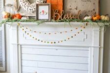 06 a bright rustic fall mantel with colorful pompom garlands, a crate with birch branches, lots of pumpkins, signs and a cotton wreath