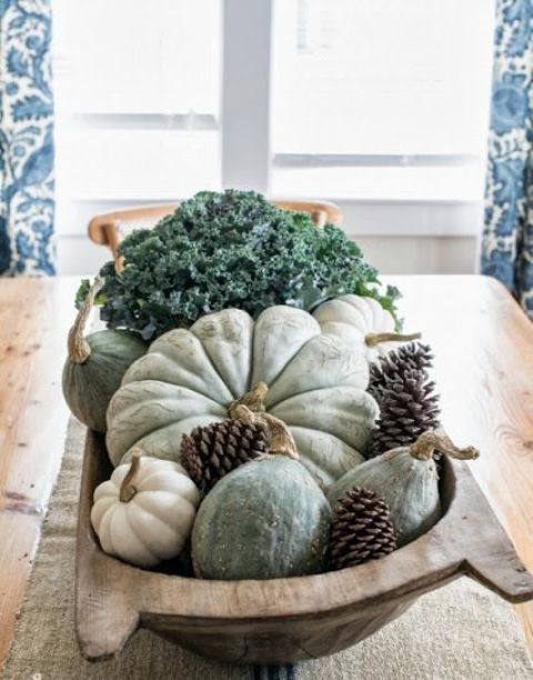 a dough bowl with pumpkins, pinecones and greenery is a cool rustic centerpiece for fall and Thanksgiving