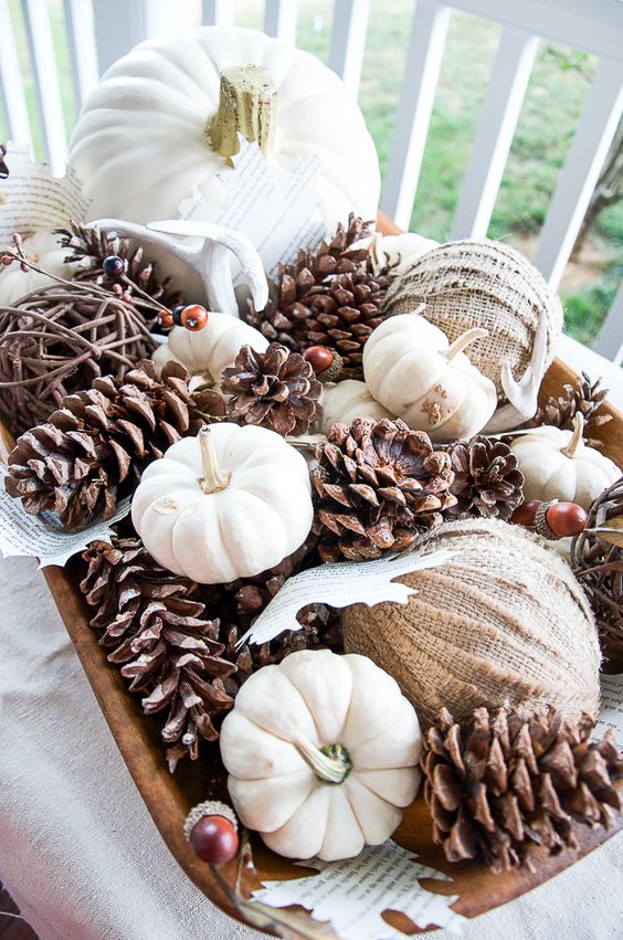 a fall centerpiece of a wooden bow, pinecones, mini pumpkins, burlap wrapped balls and acorns is cool