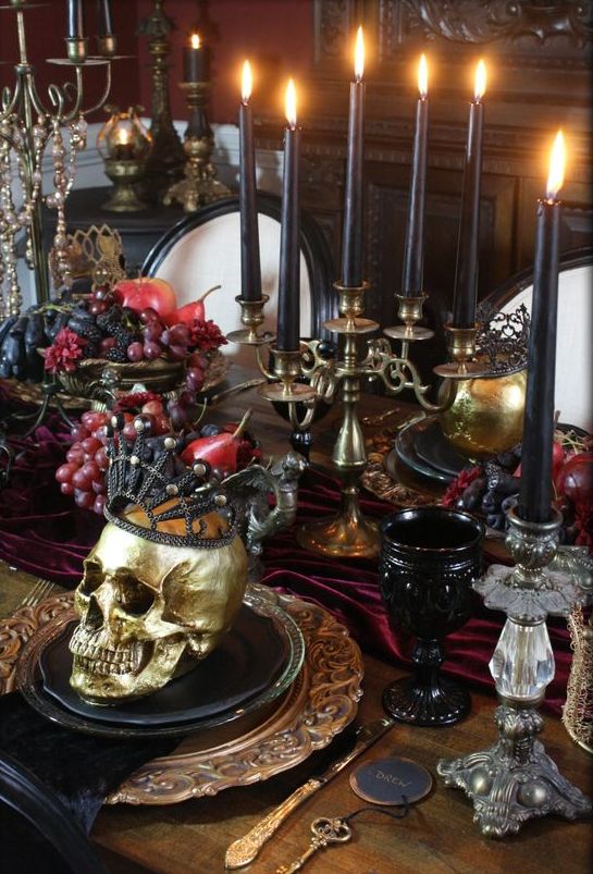 a jaw dropping vampire Halloween tablescape in burgundy, black and gold, with a skull in a crown, some fruit and black candles