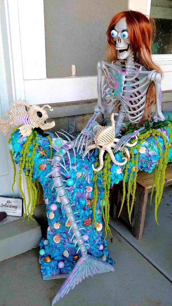 a Halloween mermaid with long hair, a skeleton fish and an octopus, a blue blanket and greenery