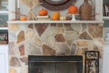 09 a chic fall mantel styled with wheat, berries, pumpkins and gourds, berry branches in a wicker vase plus a basket next to the fireplace