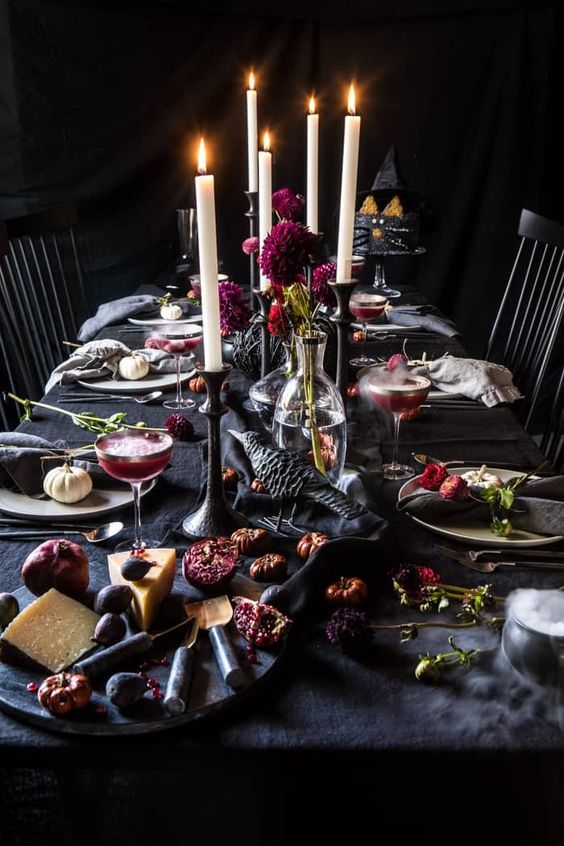 a moody and refined Halloween vampire tablescape with black textiles, black candleholders, deep purple blooms and moody food
