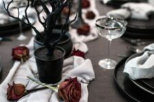 10 a mystical vampire Halloween table setting with dried red roses, black trees in black planters and black plates