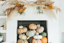 11 a contemporary fall fireplace styled with lots of heirloom pumpkins stacked on each other and with a grass arrangement over it