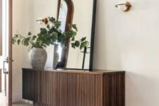 11 a cool stacked reeded console table with an oversized mirror, a planter with greenery and a sconce is a cool idea