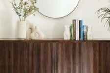12 a dark-stained sideboard with beautiful decor, vases, books and a round mirror over it is a stylish and catchy idea