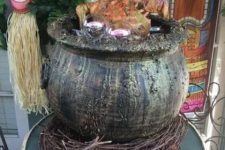 13 a tropical Halloween decoration of a cauldron with a skeleton and some branches under it is a cool idea