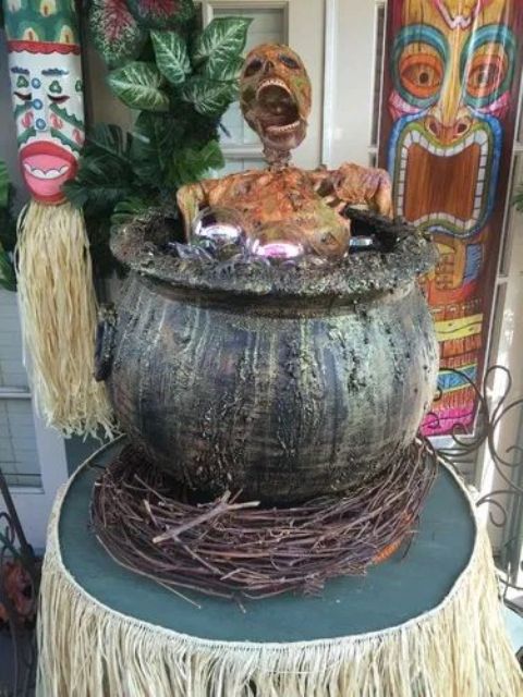 a tropical Halloween decoration of a cauldron with a skeleton and some branches under it is a cool idea