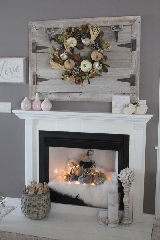 a fall fireplace styled with faux fur, fabric pumpkins and lights, a basket with firewood, candles and vases is a beautiful idea
